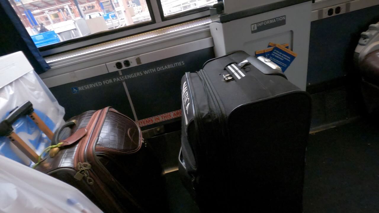 Two rolling luggages occupy the space marked as ♿ RESERVED FOR PASSENGERS WITH DISABILITIES.